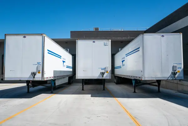 trailers unloading cargo into industrial warehouse in new england